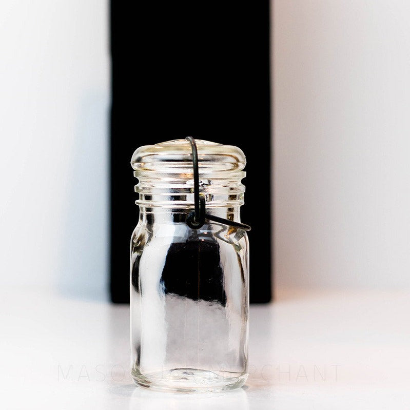 Close up of a Vintage 1930s half pint wire bail mason jar against a white background