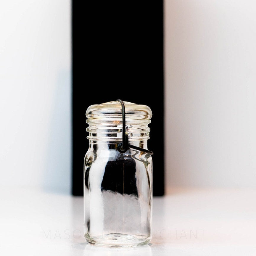 Side view of a Vintage 1930s half pint wire bail mason jar against a white background