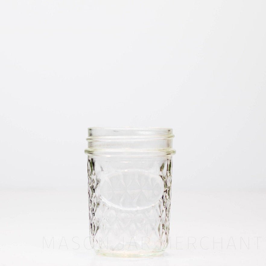 Regular mouth half pint mason jar with a quilted pattern and space to add a label, against a white background