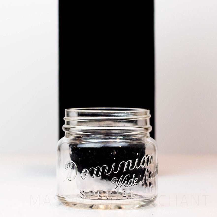 A close up of a Vintage wide mouth pint mason jar with Dominion Special logo, against a white background