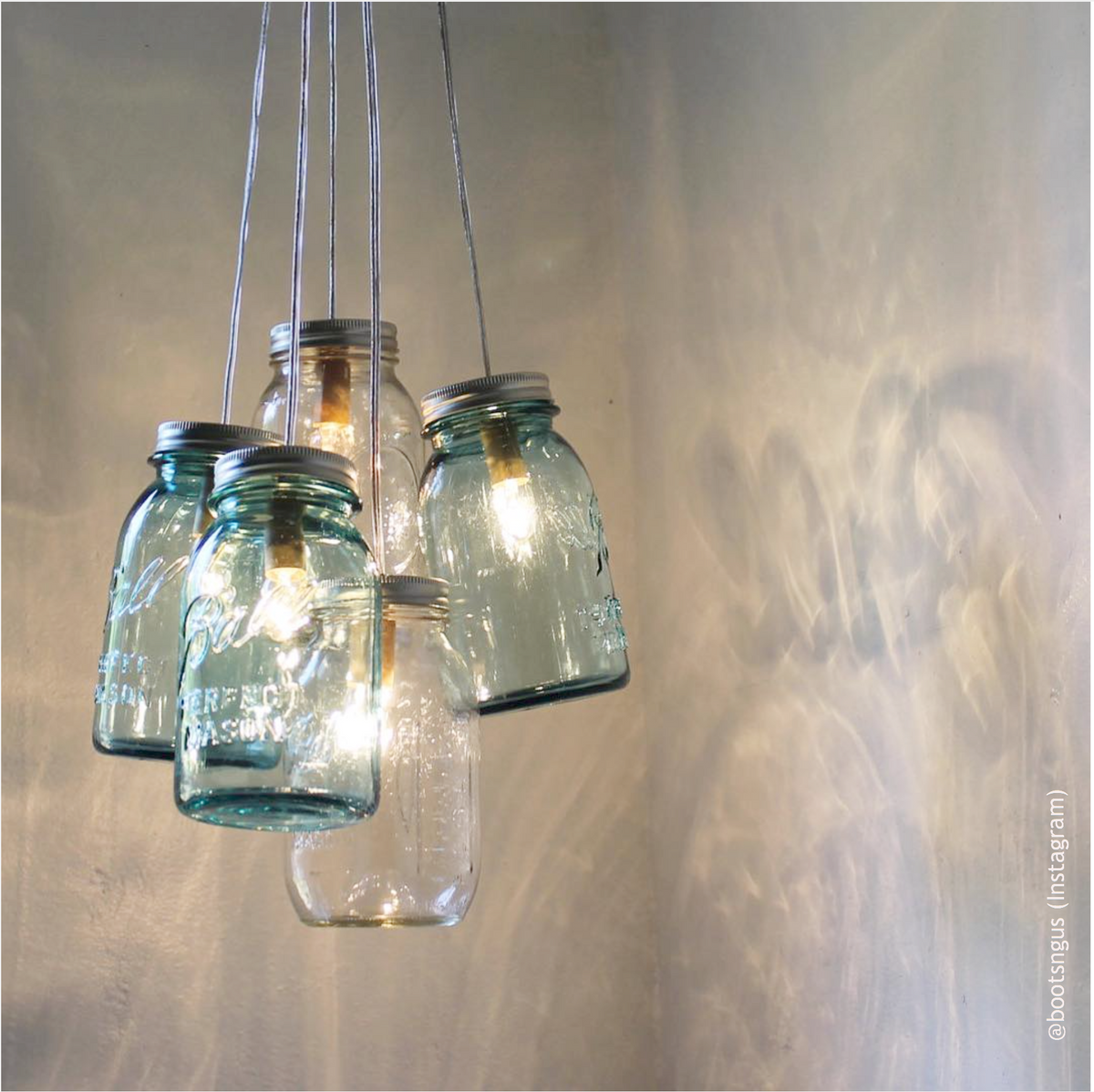 Vintage blue Ball regular mouth quart mason jars hanging on the ceiling to look like a chandelier. There is bulbs inside it.