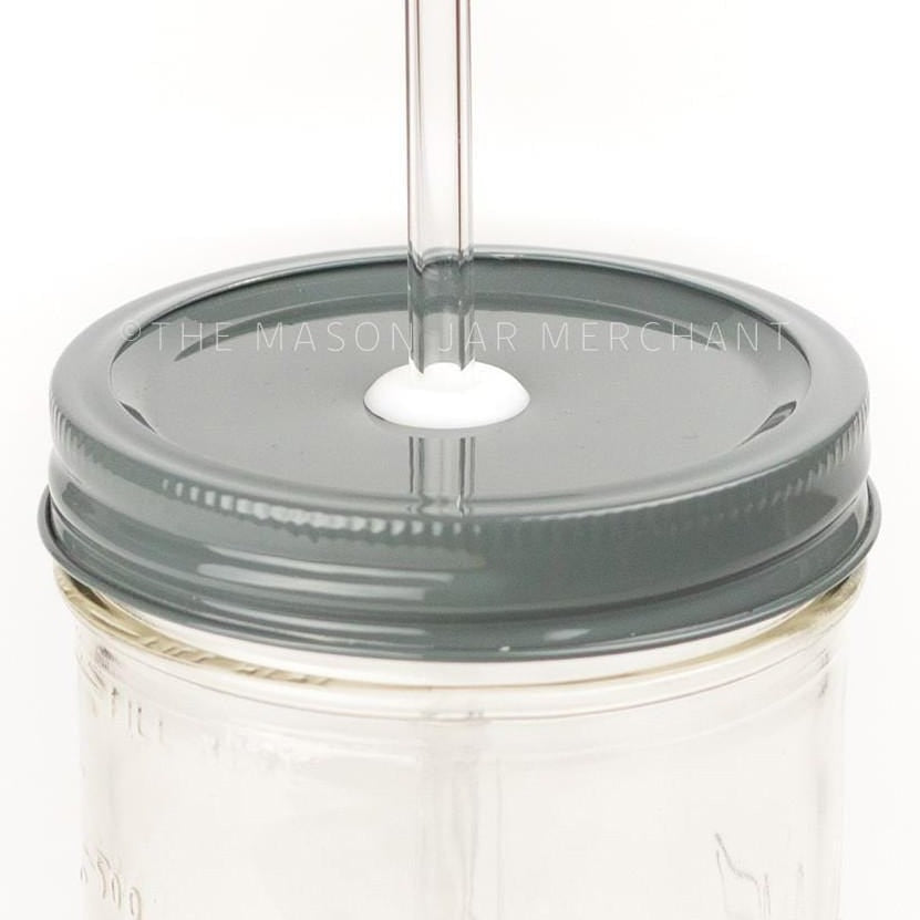 Close-up of a 24 oz wide mouth mason jar with a dark gray custom painted lid with a white silicone grommet and a glass straw, against a white background