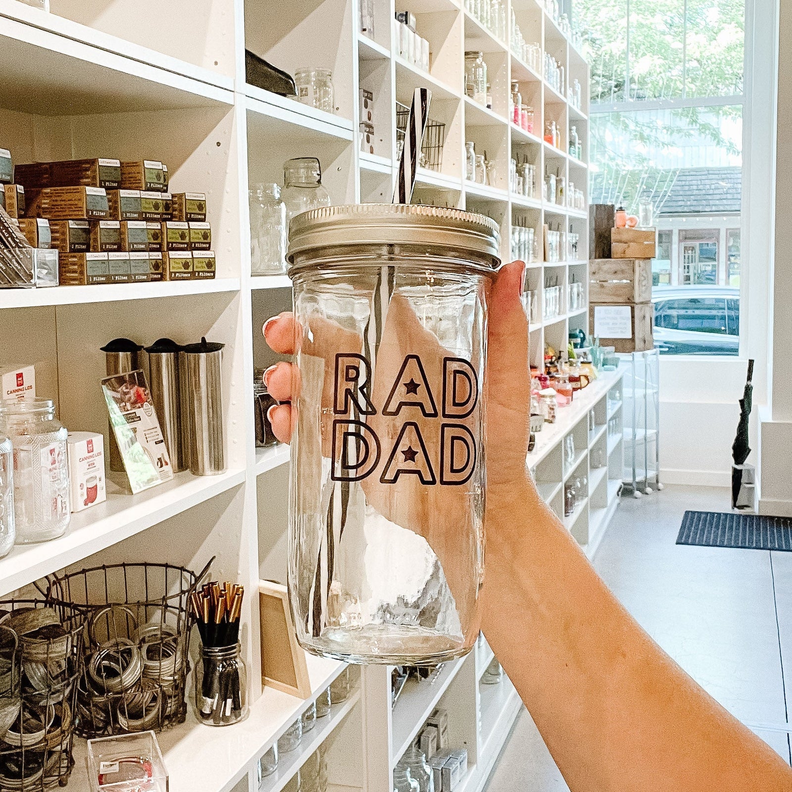 hand holding a mason jar tumbler that says "RAD DAD"