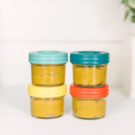 4 oz mason jar bottles with baby food and covered with lids in Paprika, Mango, Aqua, and Ocean. All stacked in twos. Photographed in a white countertop.