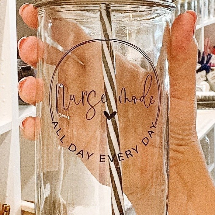 Close up of a hand holding a mason jar tumbler that says “nurse mode, all day every day”