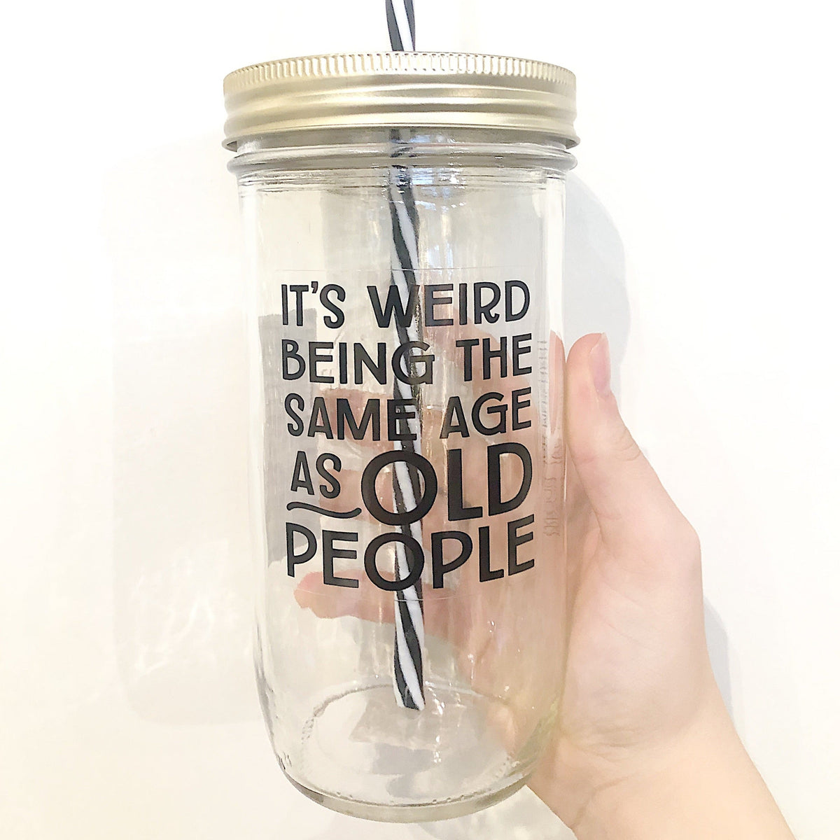Hand holding a mason jar tumbler that says “It’s weird being the same age as old people”