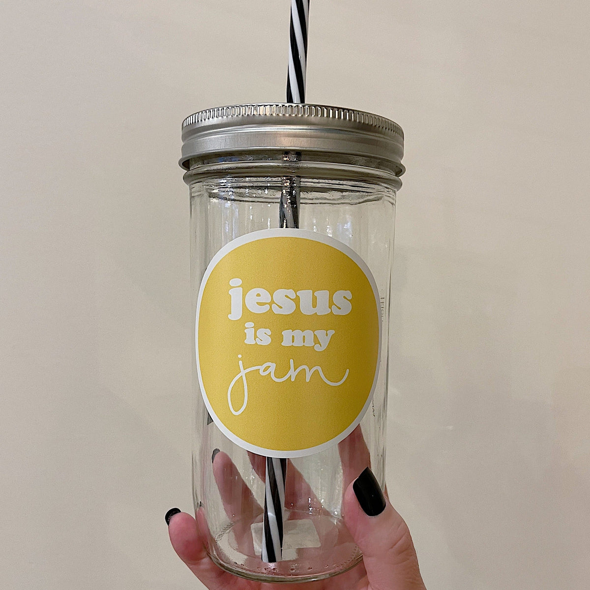 Mason jar tumbler that says “jesus is my jam” in white writing on a yellow circular backgroun