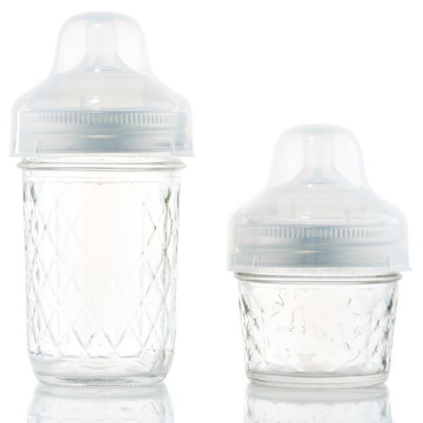 close up of baby holding a half pint glass reusable mason jar with silver ring and rubber bottle lid