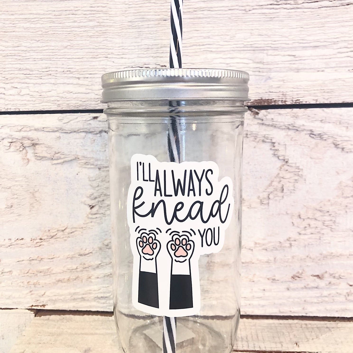 A mason jar tumbler that says “I’ll always knead you” with two cat arms and paws.