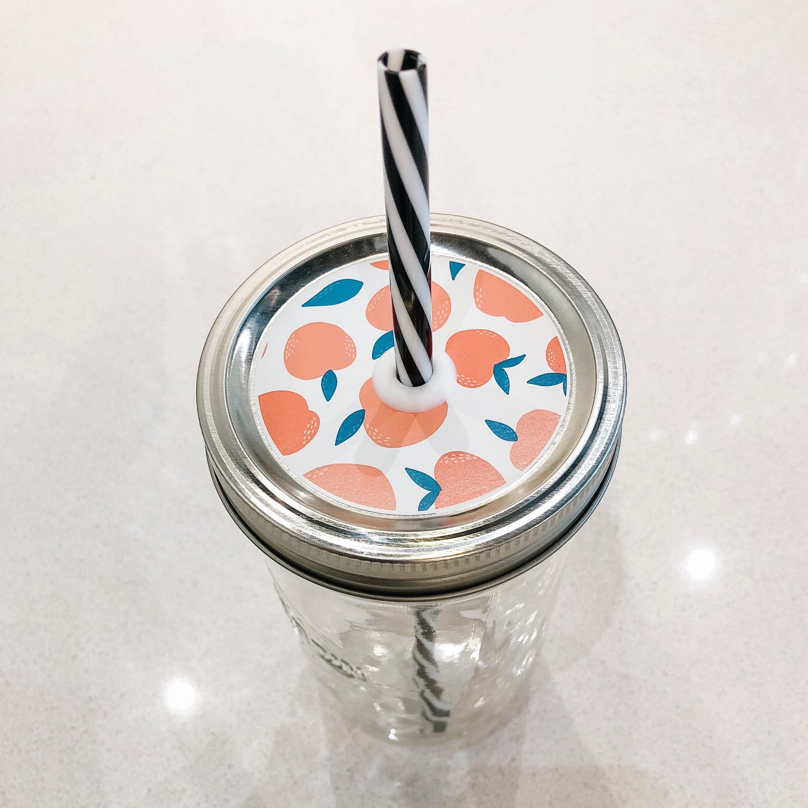 Photo of mason jar straw lid with peaches on print.