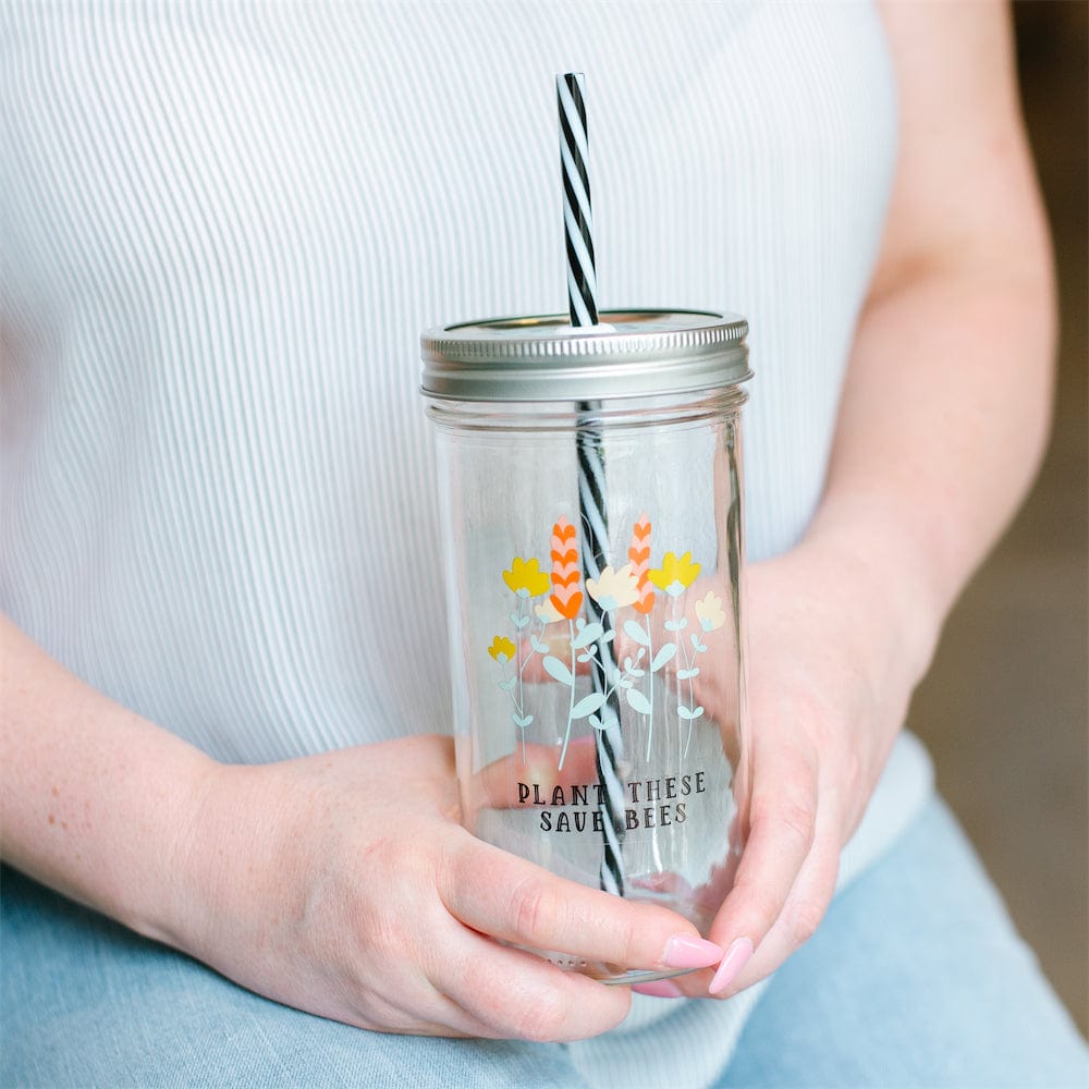 Photo of a mason jar tumbler with a print of flowers and a text that says "plant these, save bees'.