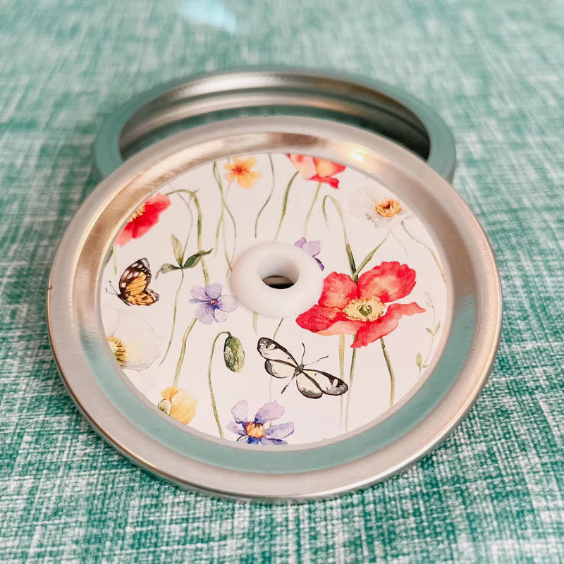 Mason jar patterned straw lid with butterflies and long stemmed flowers on white background 