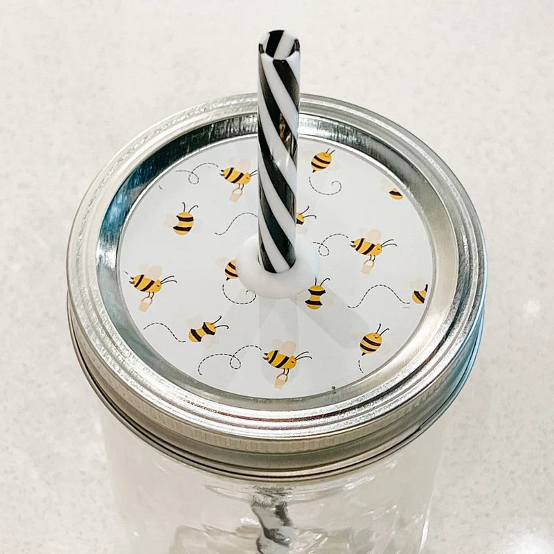 Picture shows mason jar patterned straw lid that has small bumble bees flying on white background 