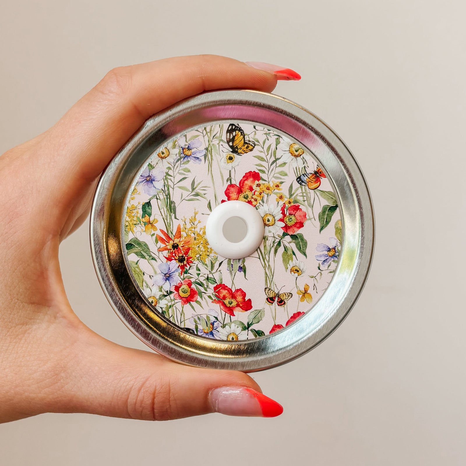 straw lid with a pink background there are flowers and butterflies arranged in a grid-like pattern