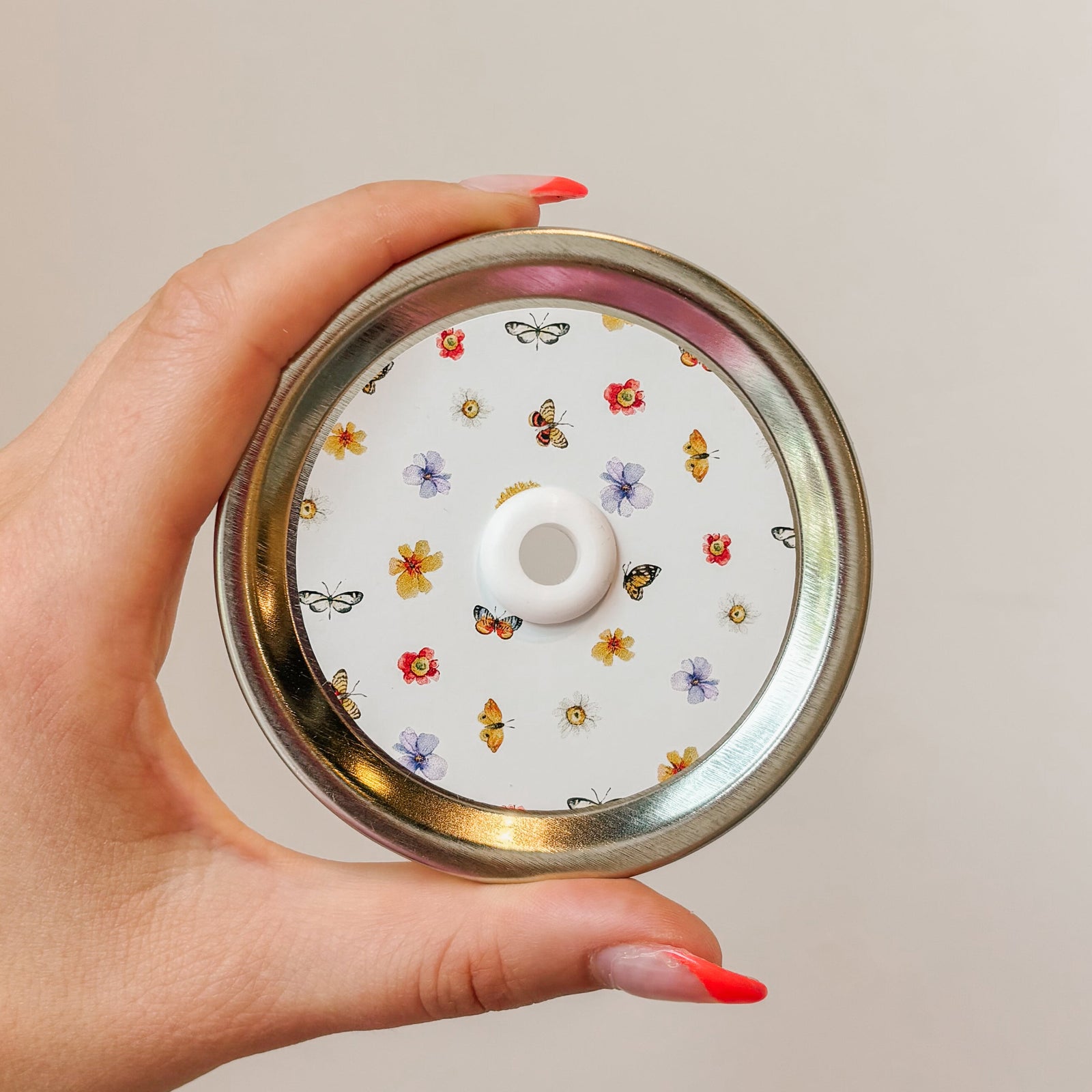 straw lid with a white background, there are flowers and butterflies arranged in a grid-like pattern