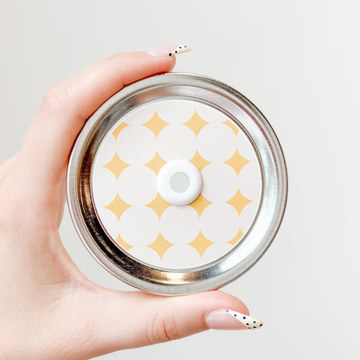 straw lid with a taupe background and yellow diamond/sparkles patterned across