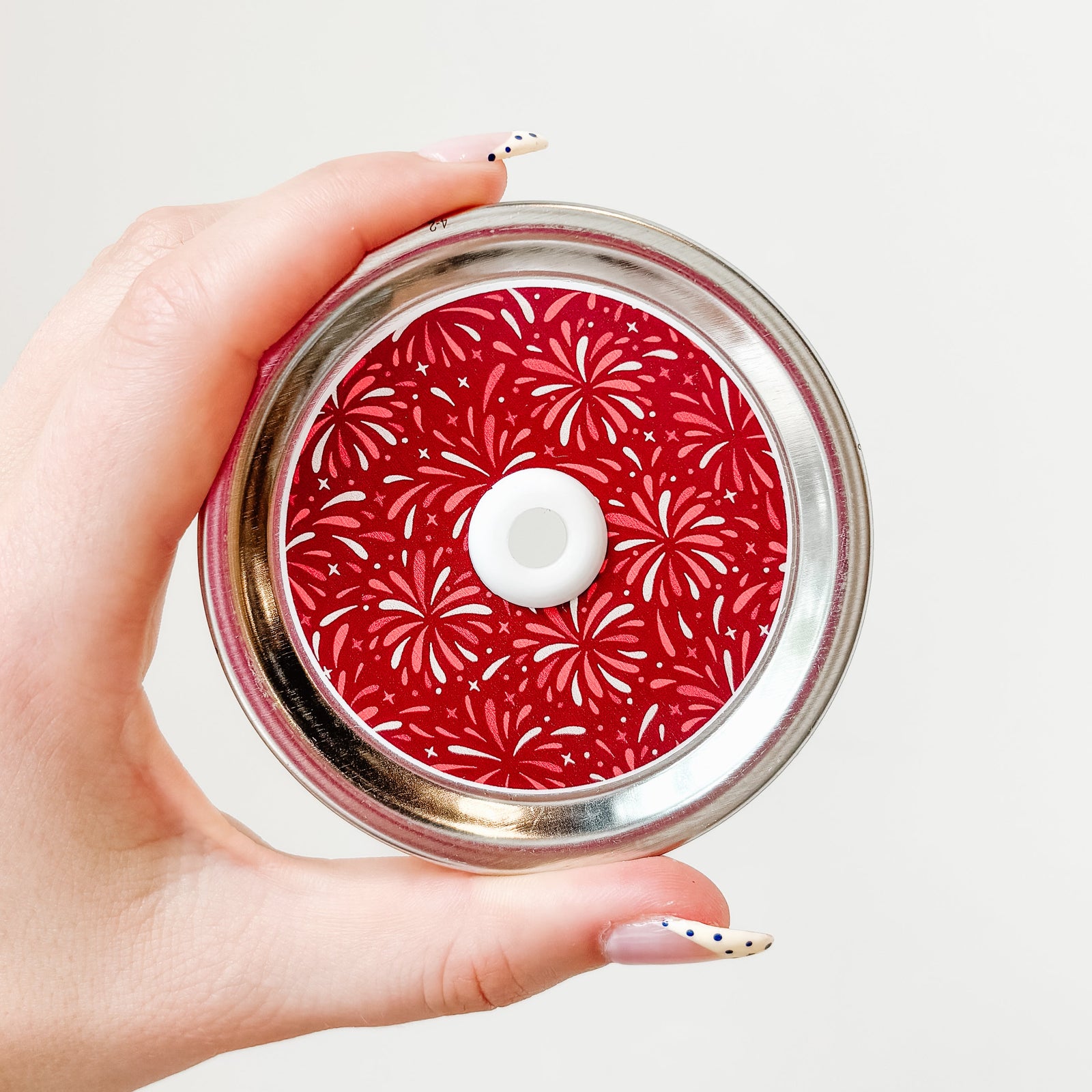 a straw lid with a dark red background with red and white fireworks across the lid