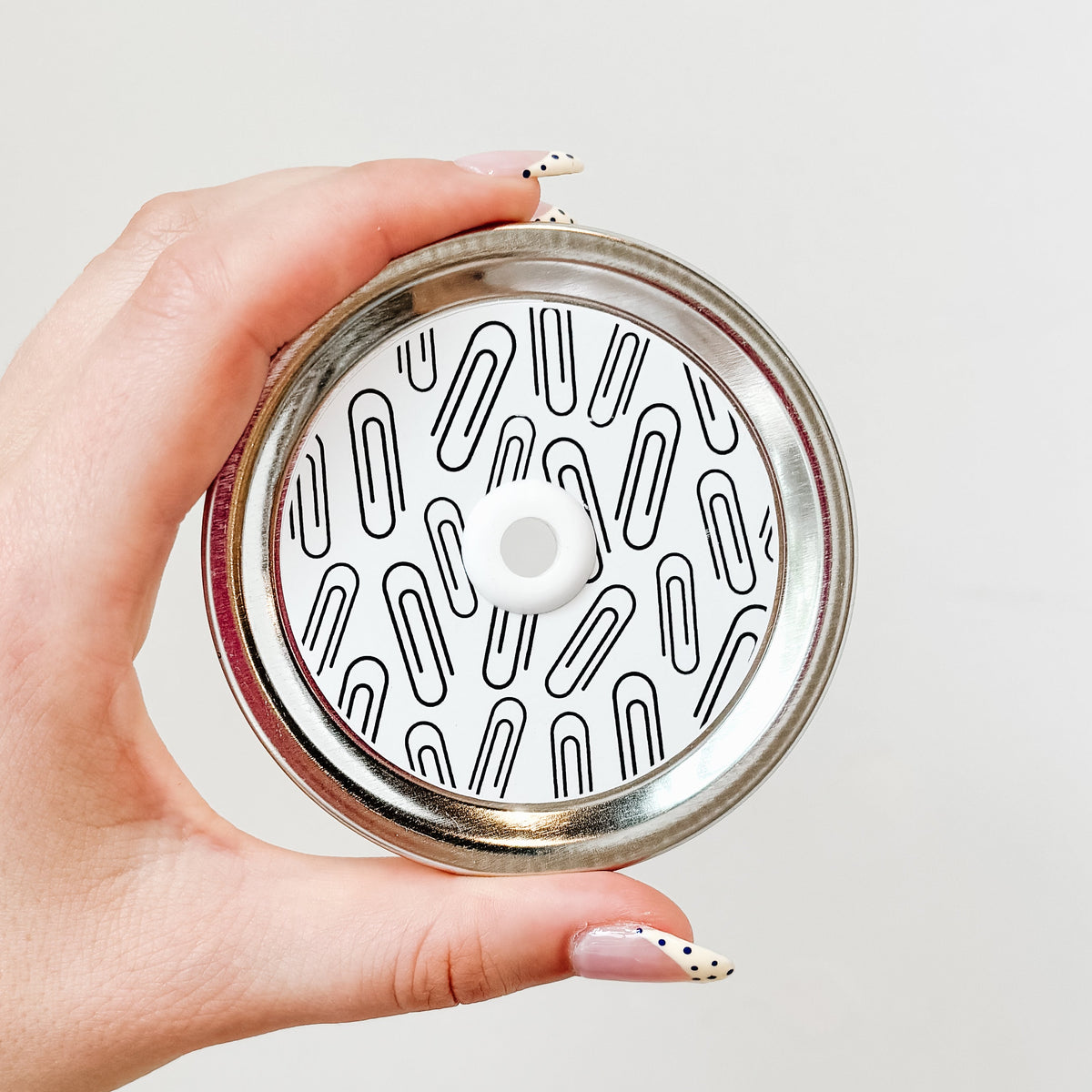 Silver lid with a paper clips on white patterned mason jar straw lid