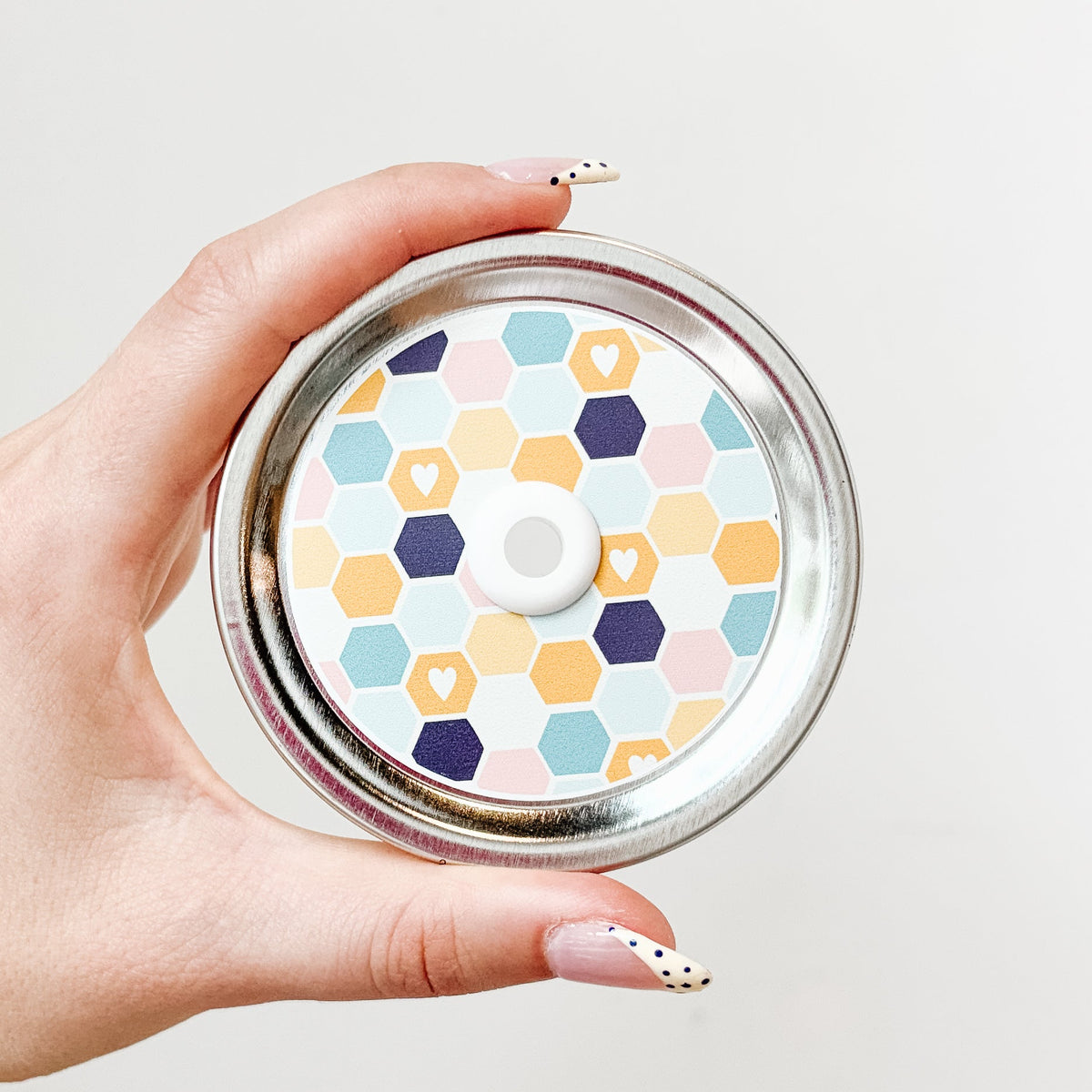 Hand holding mason jar straw lid with multicolour honeycomb lid design with small hearts
