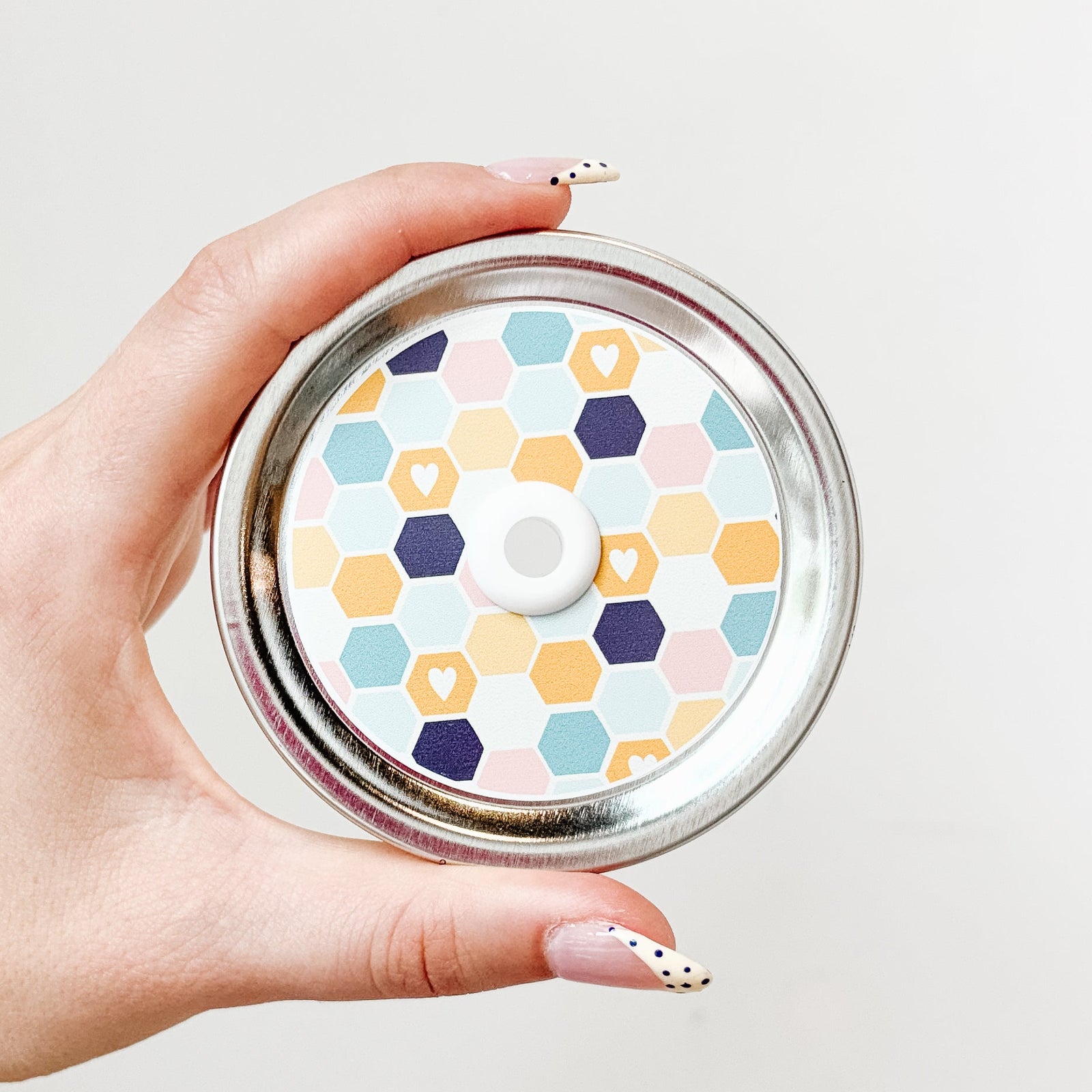 Hand holding mason jar straw lid with multicolour honeycomb lid design with small hearts