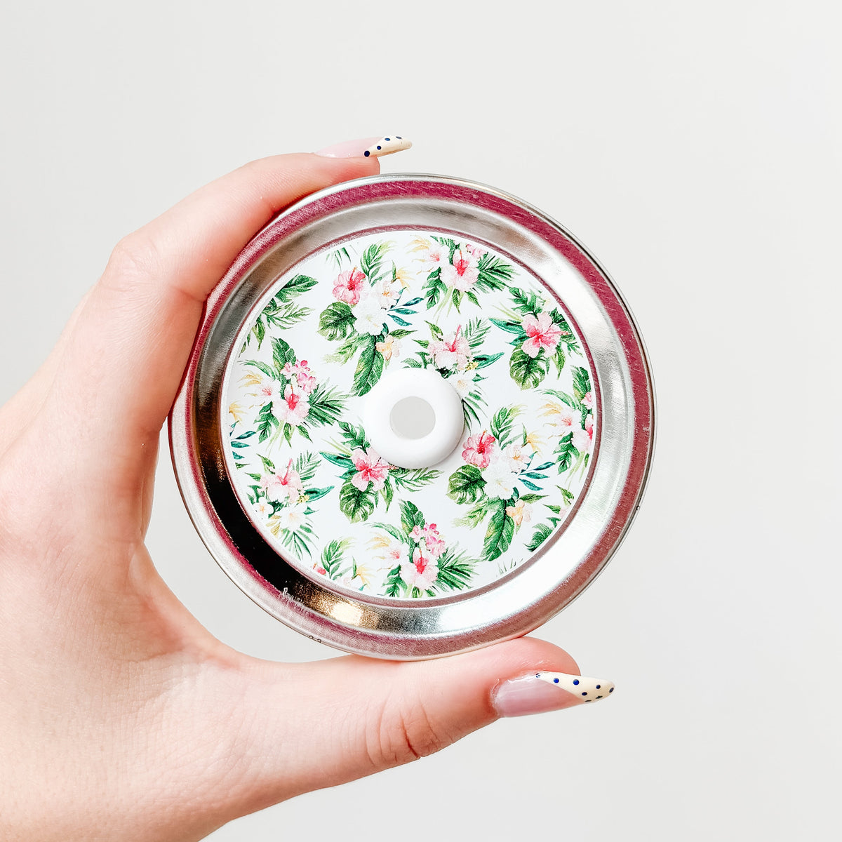 Mason jar straw lid with silver ring and a white sticker that has palm leaves and hibiscus flowers in print