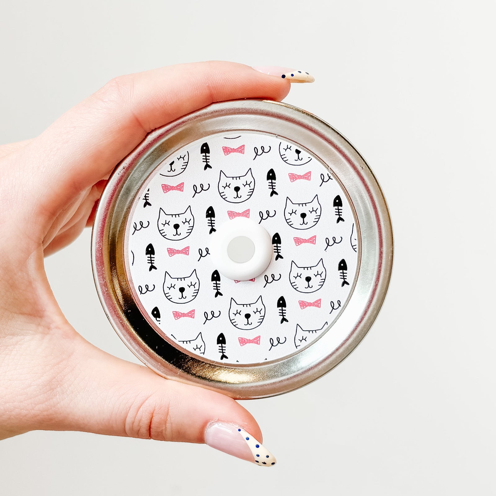 straw lid with white background, line drawings of cat faces, fish skeletons, and pink bow ties
