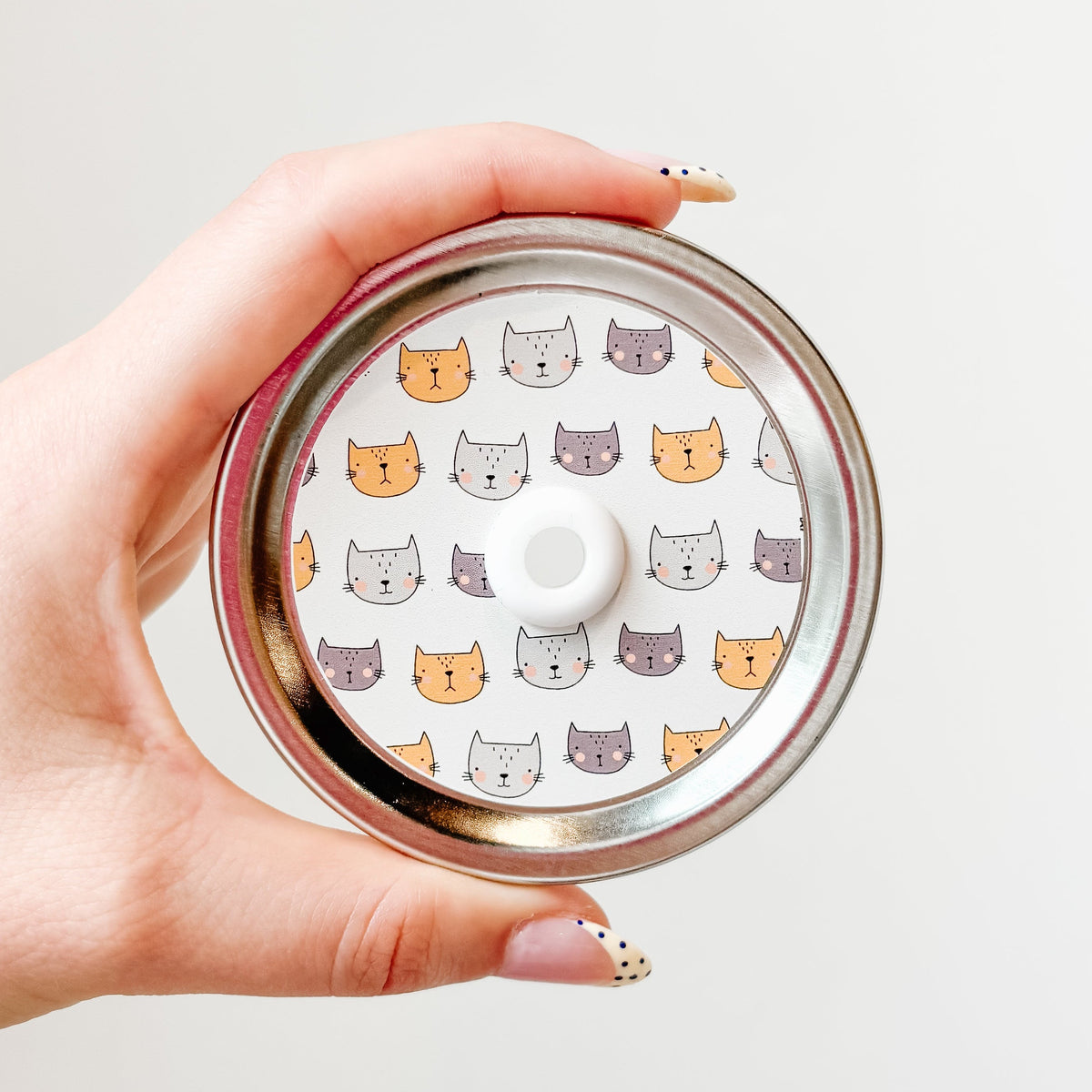 straw lid with a white background and orange, grey, and dark grey cat faces repeating across