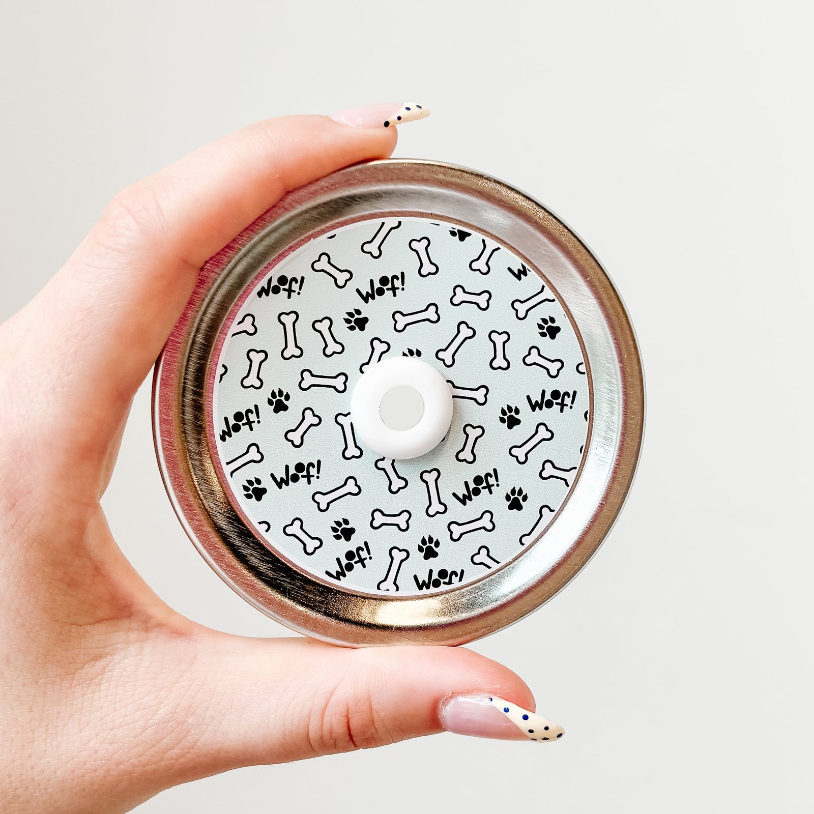 straw lid with light blue background, white dog bones, black paw prints, and "woof!"