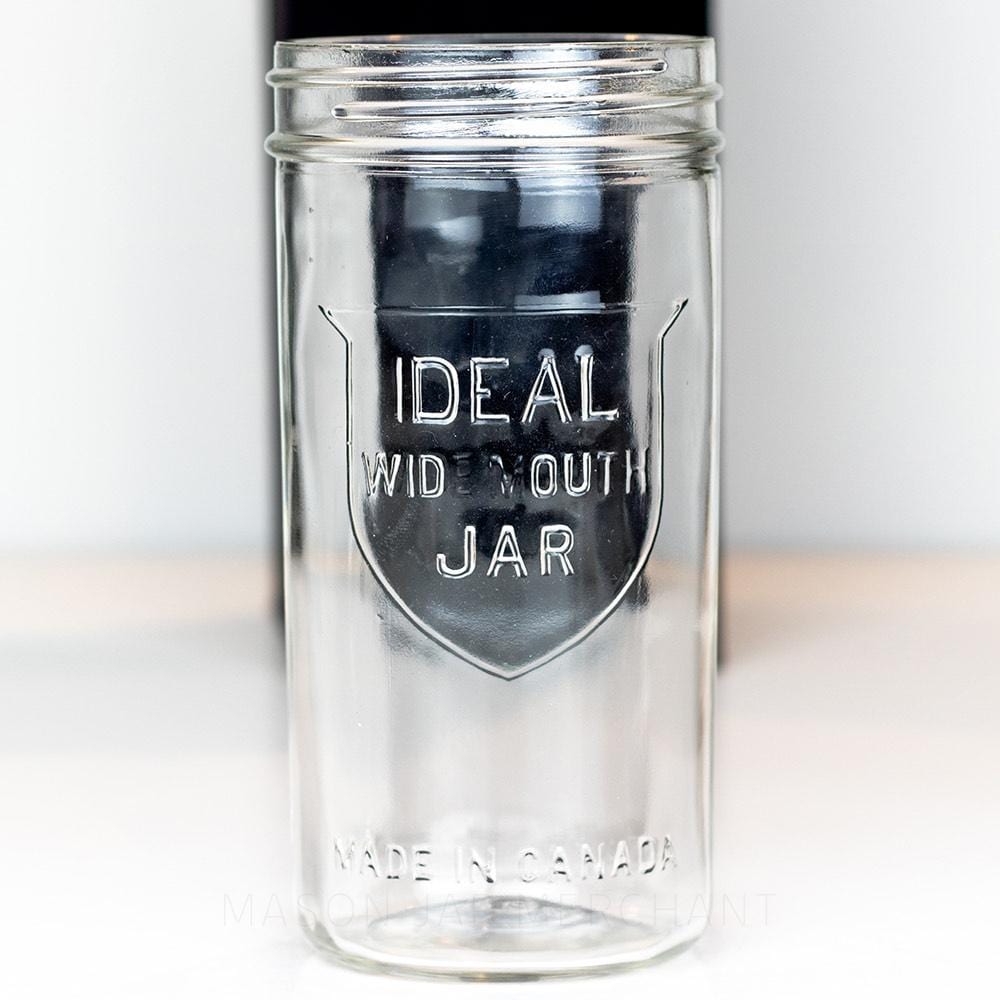 Ideal brand wide mouth 24 oz mason jar with shield logo on front, on a white background