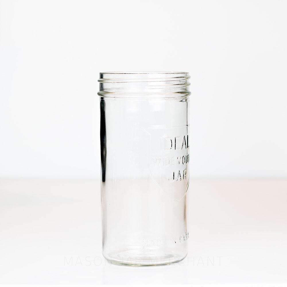 side view of a Ideal brand wide mouth 24 oz mason jar with shield logo on front, on a white background