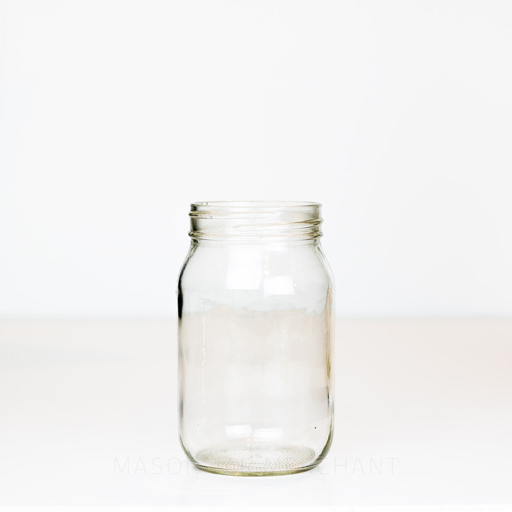 Regular mouth pint mason jar with plain sides on a white background