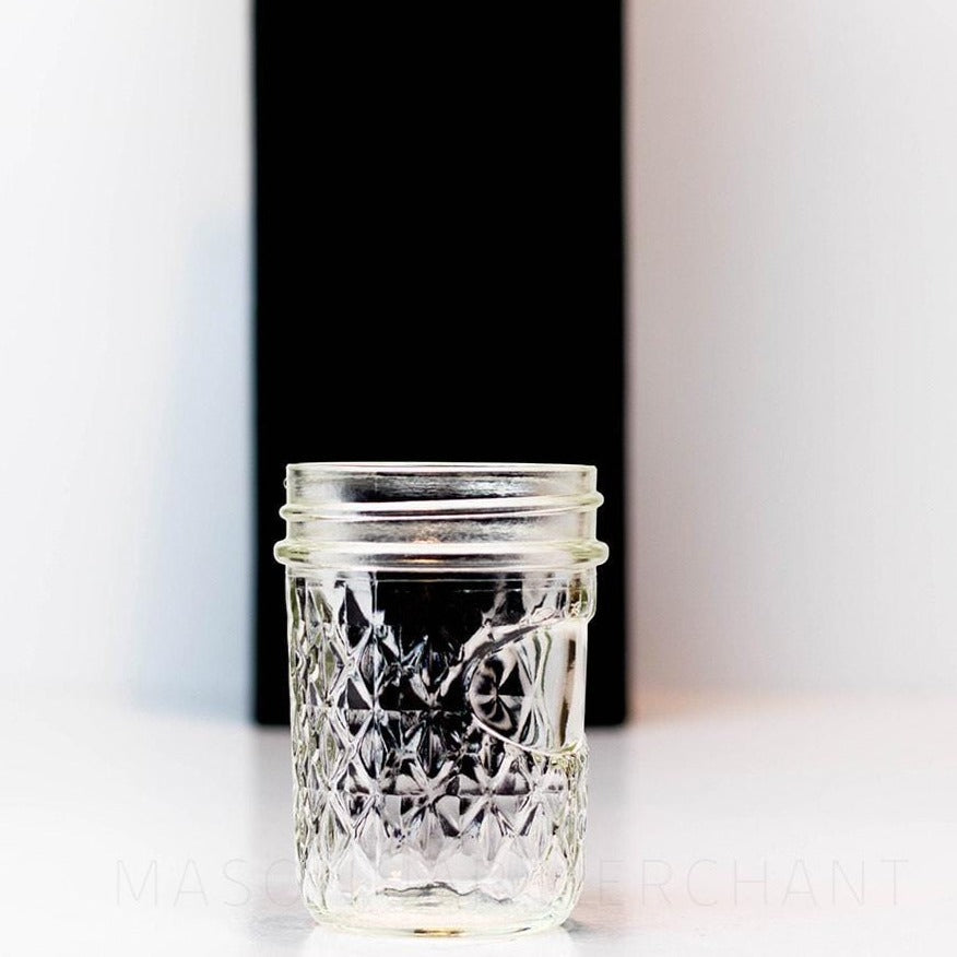 Regular mouth half pint mason jar with a quilted pattern and space to add a label, against a white background