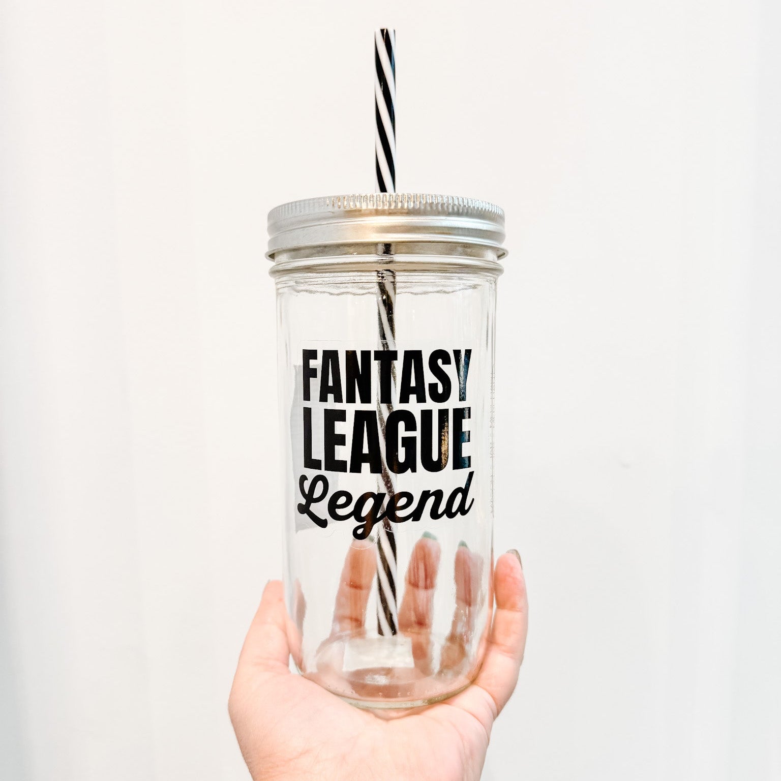 Clear tumbler with 'Fantasy League Legend' text held by a hand against a white background