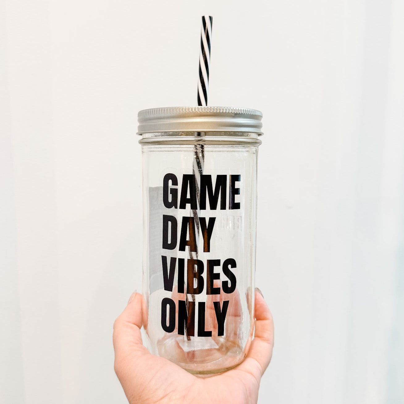 Clear tumbler with 'Game Day Vibes Only' text held by a hand against a white background