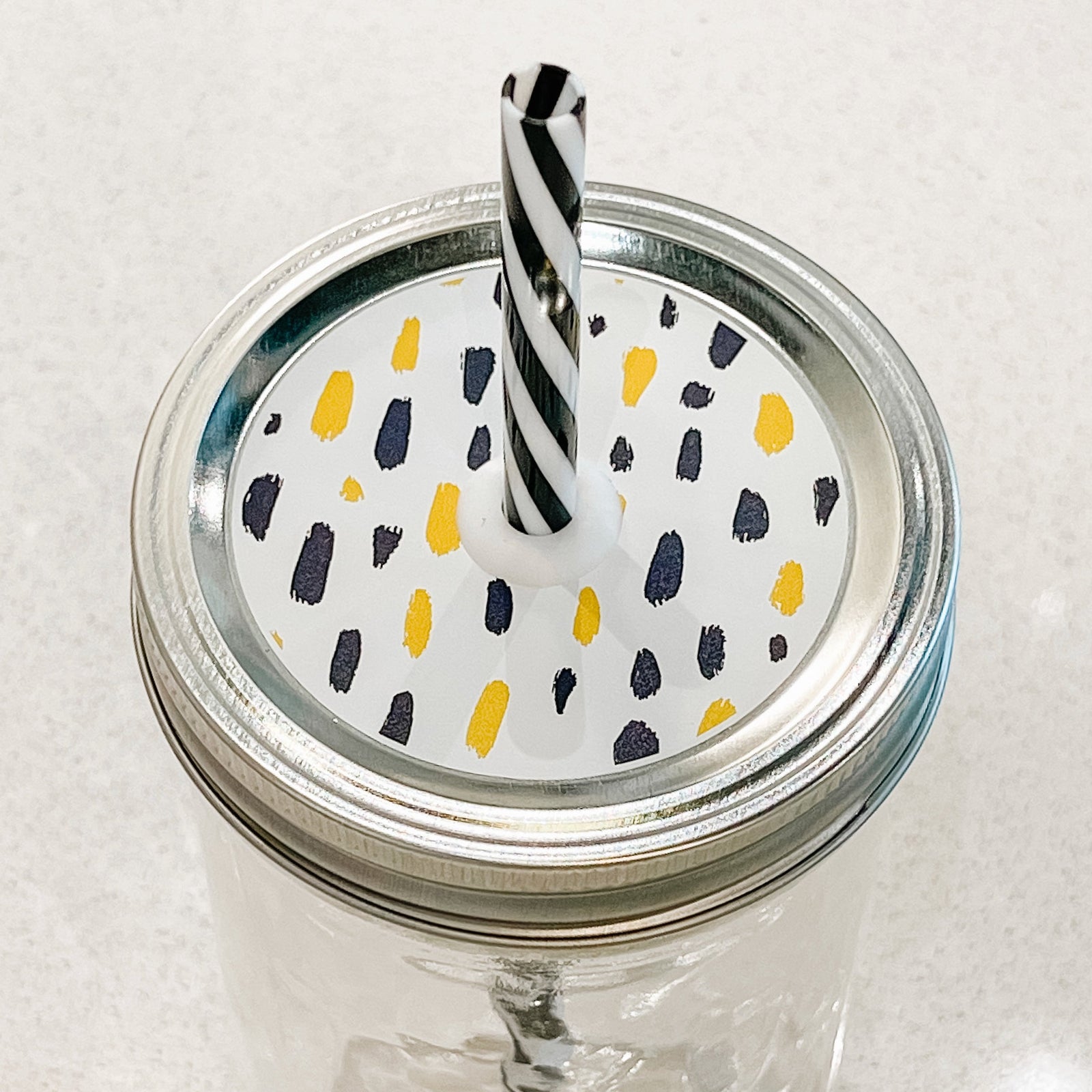 top photo of mason jar lid with black and yellow brush marks