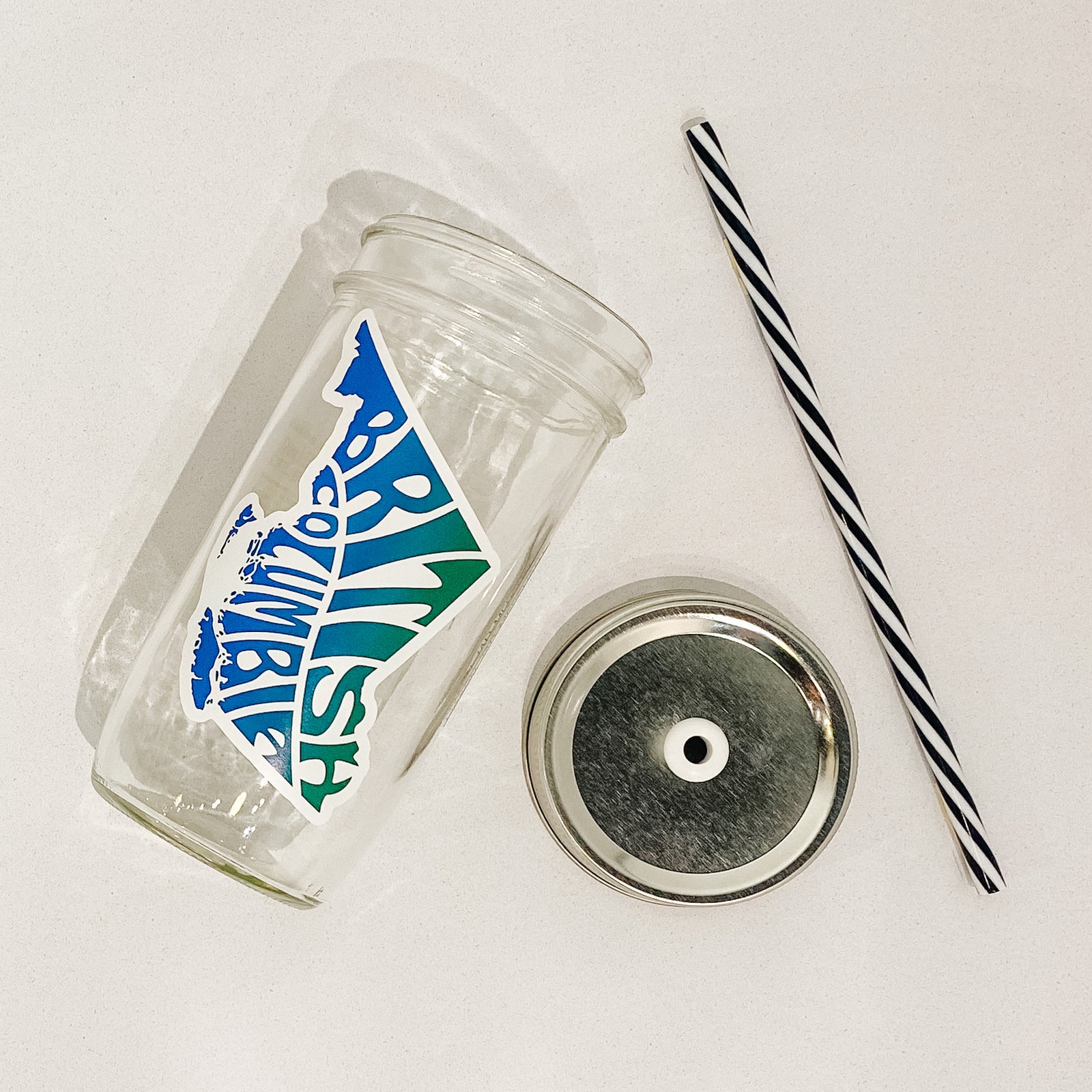 Hand holding mason jar that reads British Columbia in the shape of the province. Colours are blue and green ombré. 