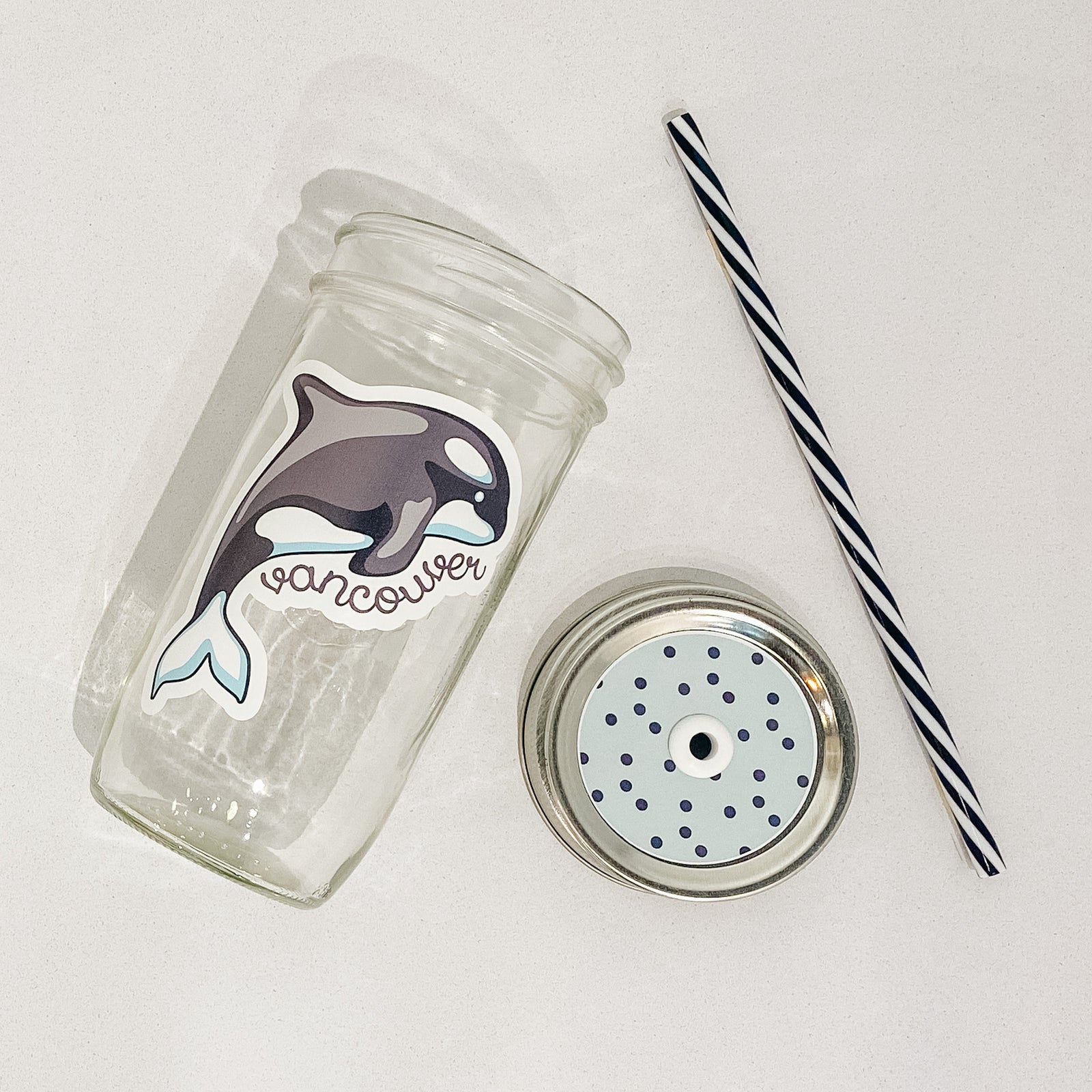 Hand holding mason jar that reads Vancouver with orca.