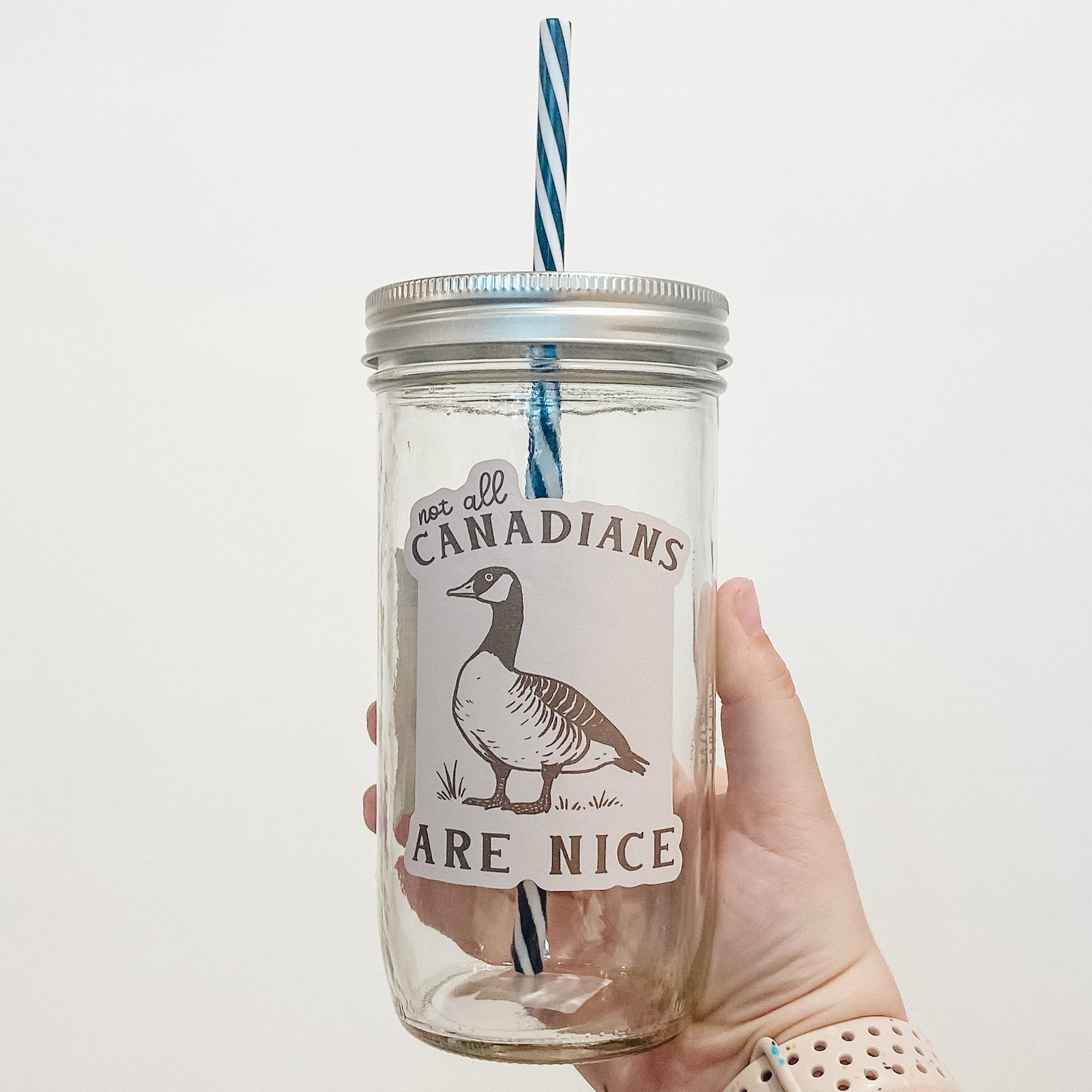 Hand holding mason jar that reads not all Canadians are nice with goose. 