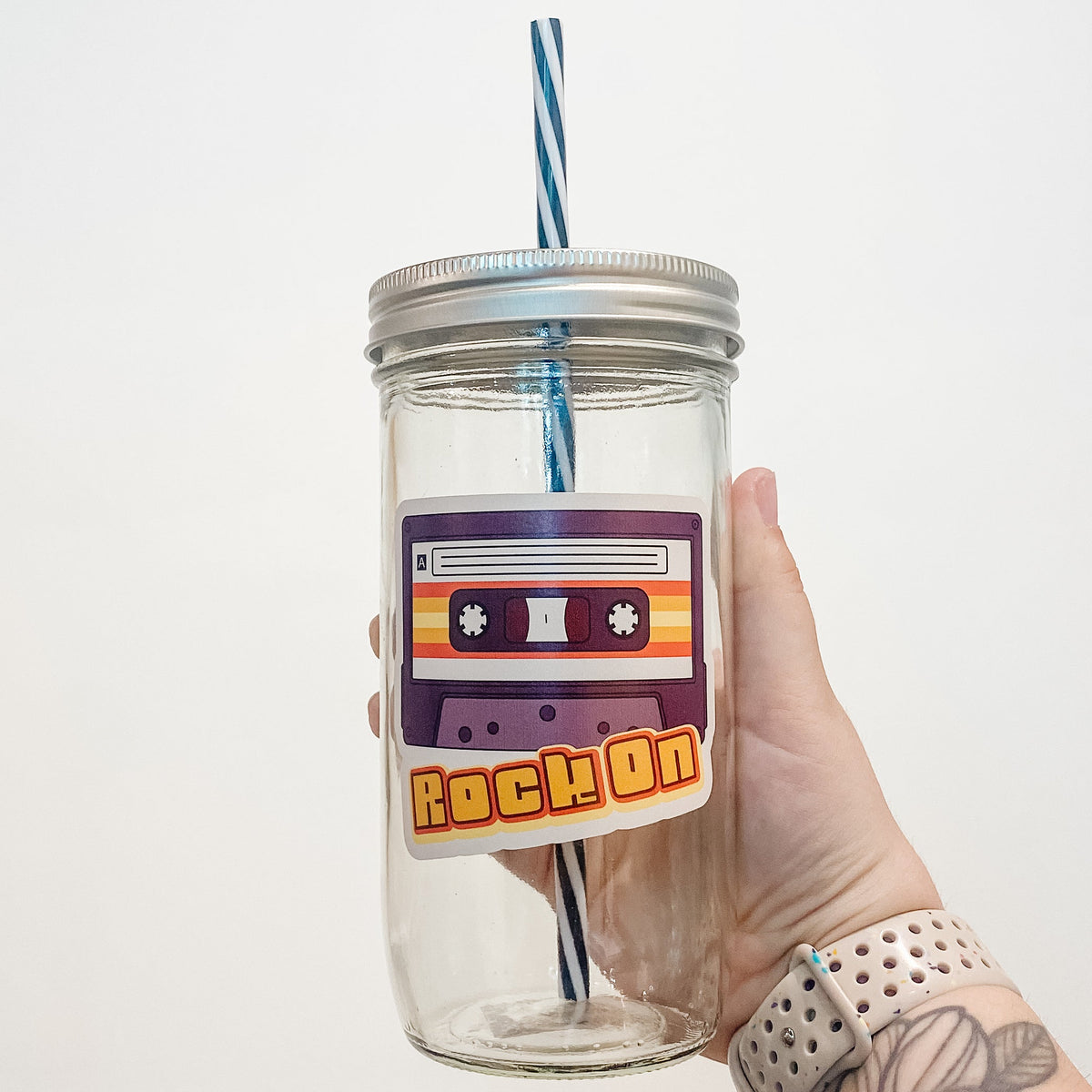 Hand holding mason jar that reads rock on with vintage cassette tape