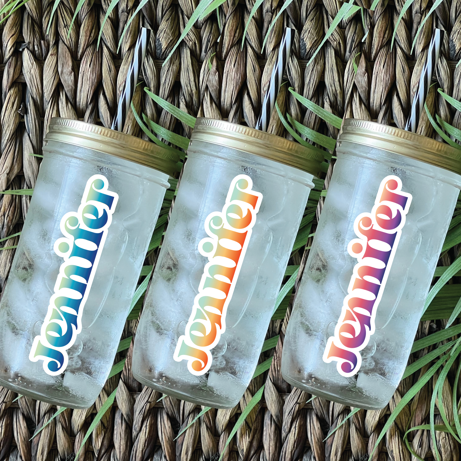 Three custom tumblers filled with iced coffee laying on a colourful beach towel.