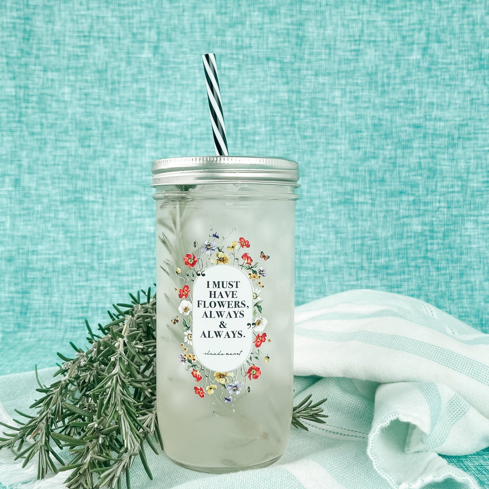 Mason jar tumbler that says "I must have flowers, always & always. -Claude Monet” with flowers creating an oval around the quote. 