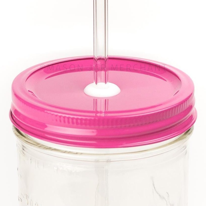 Close-up of a 24 oz wide mouth mason jar with a hot pink custom painted lid with a white silicone grommet and a glass straw, against a white background