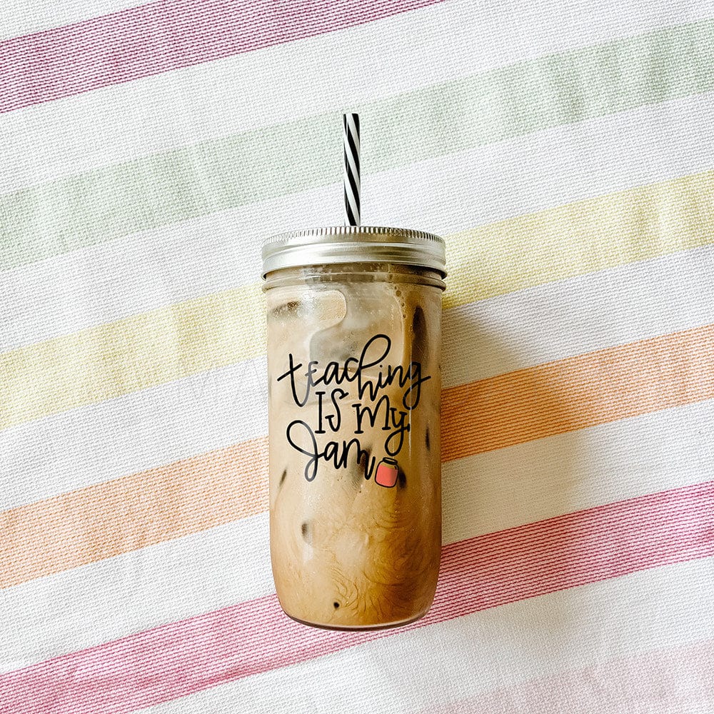 Tumbler with iced coffee with print that says "Teaching is my jam" with a jam beside the text as a design. Photographed against a backdrop of a striped fabric..