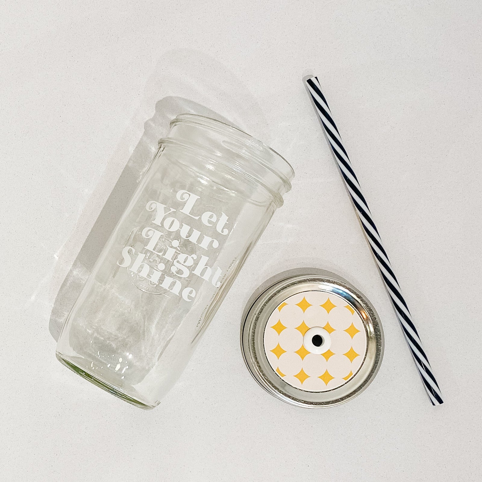 Mason jar tumbler that says “let your light shine” in white letters on a clear background