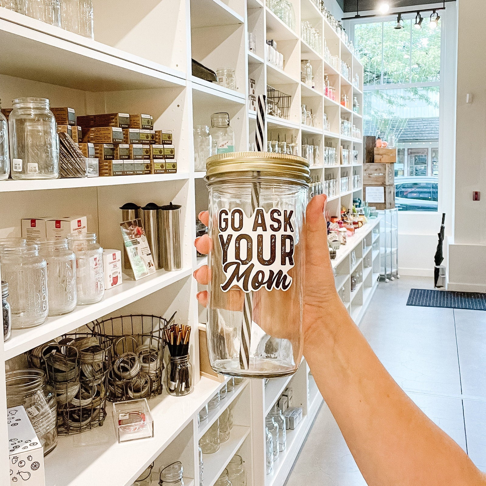 Hand holding a mason jar tumbler that says “go ask your mom”