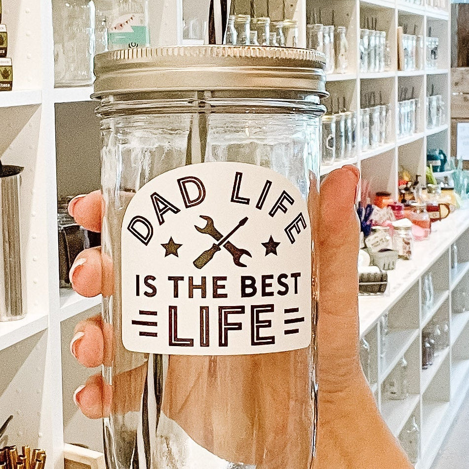 Hand holding a glass jar with a label in a store setting