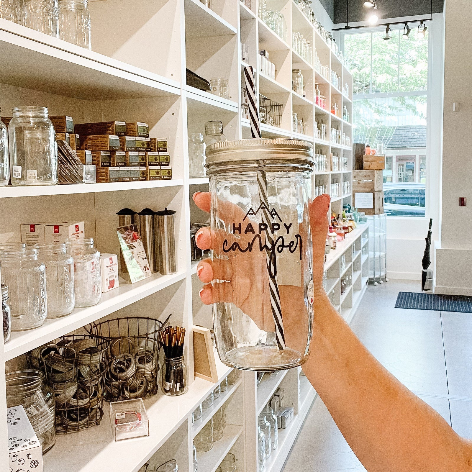 Mason jar tumbler that says “happy camper” with three mountain peaks above