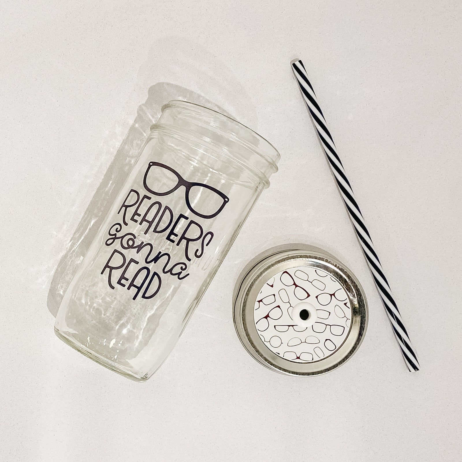 Mason jar tumbler that says “readers gonna read” with a pair of glasses above the text