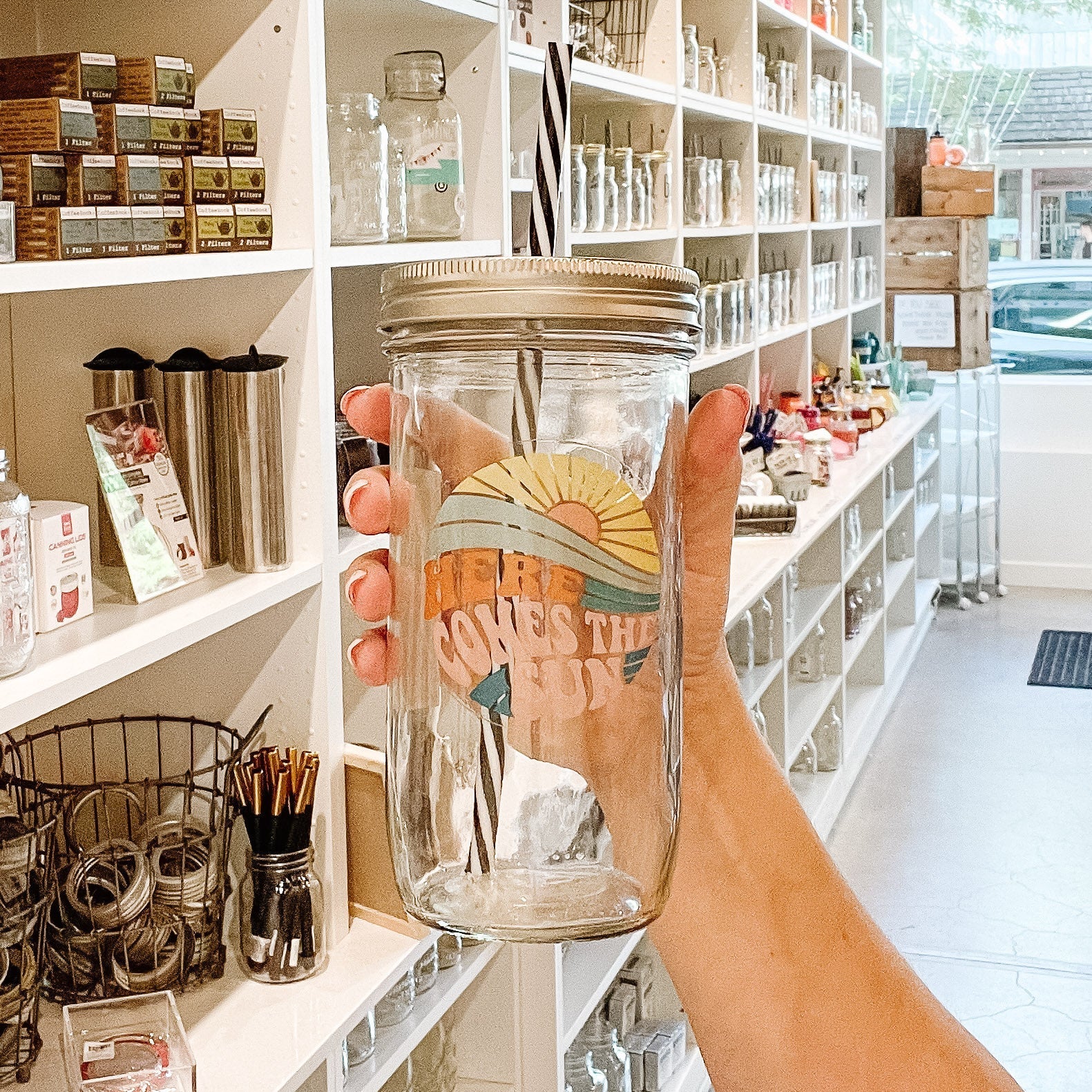 Mason jar tumbler that has the image of a sun rise and says “here comes the sun”