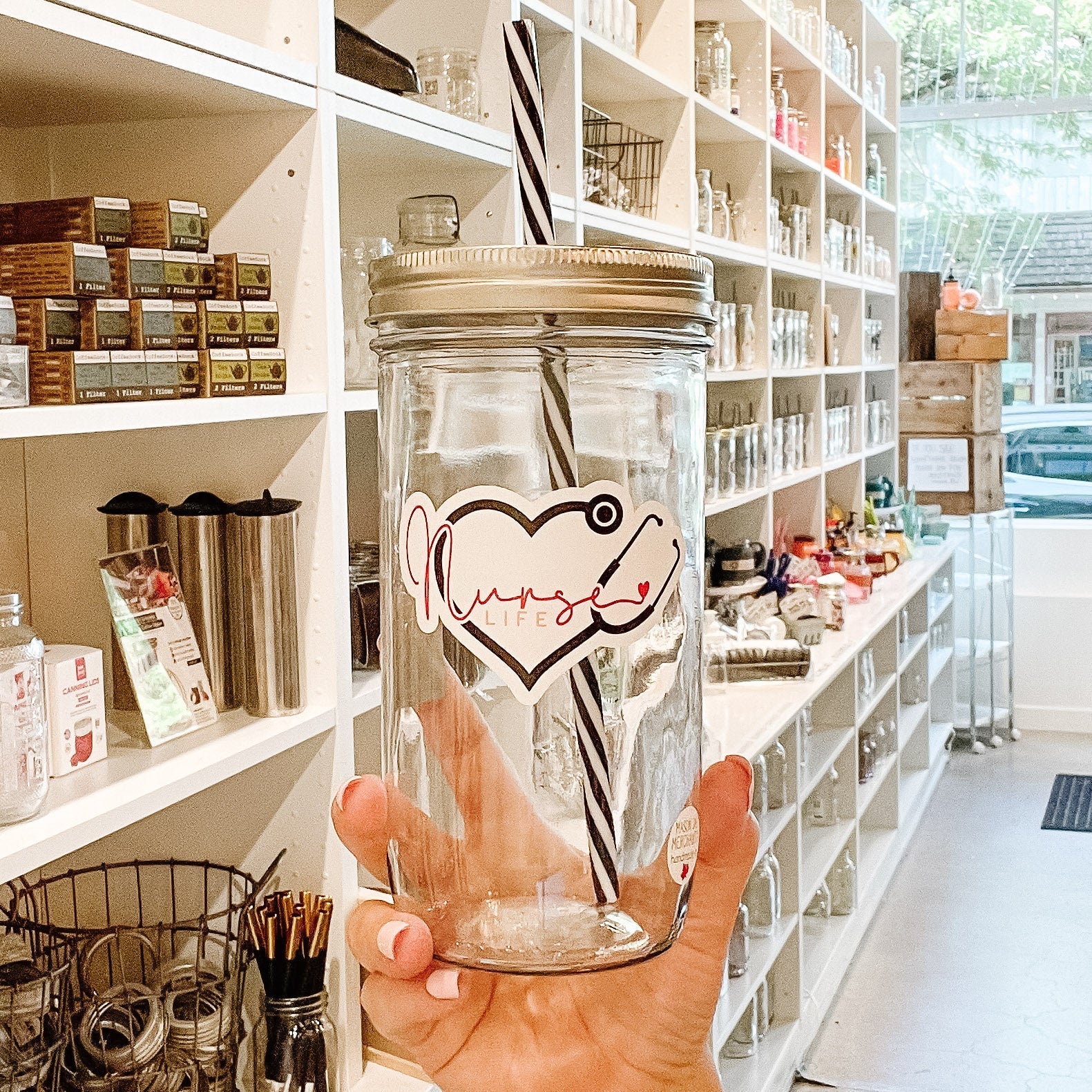 Hand holding a mason jar tumbler that says "nurse life” within a heart made out of a stethoscope